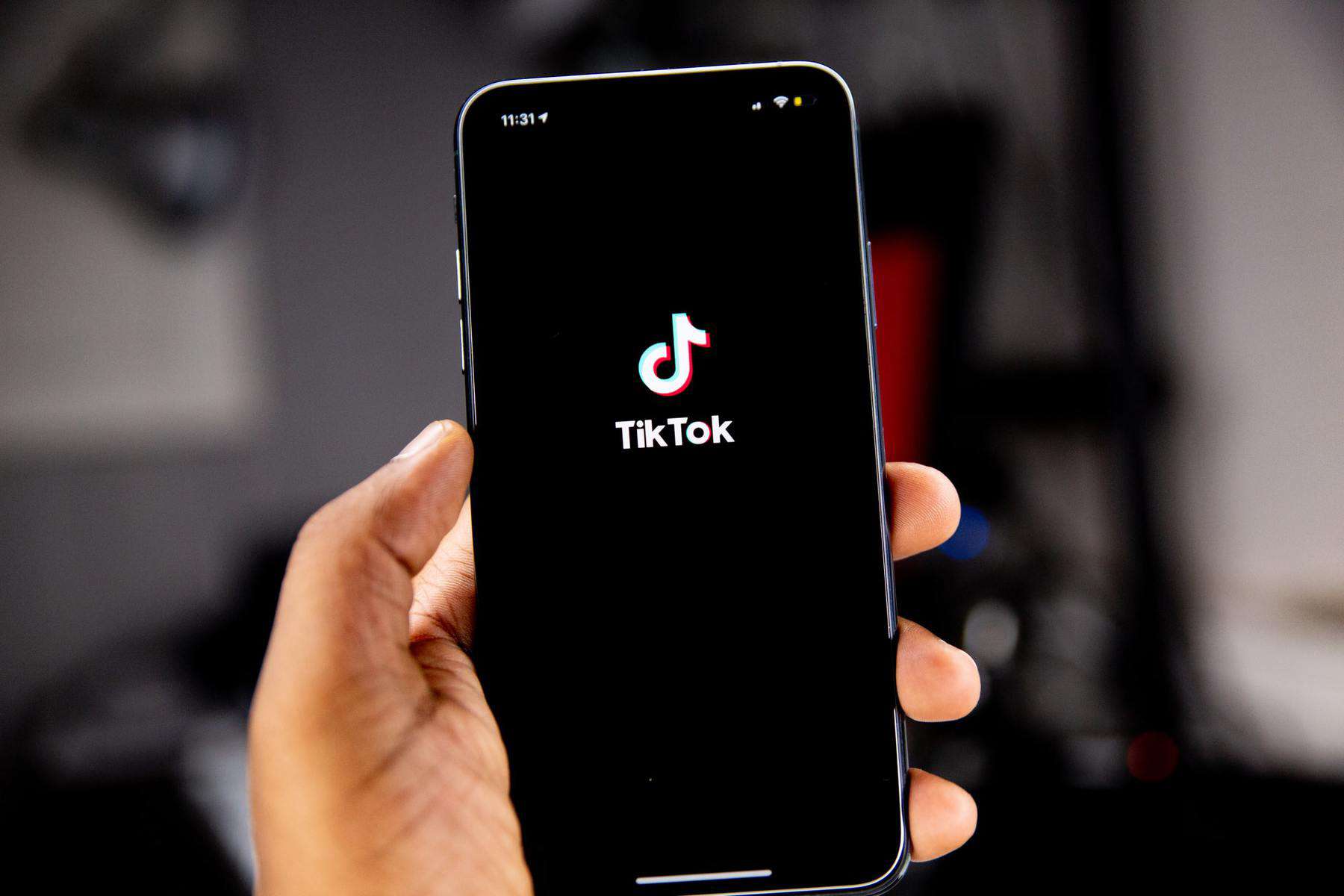 Person holding phone with TikTok logo - Theme Circle