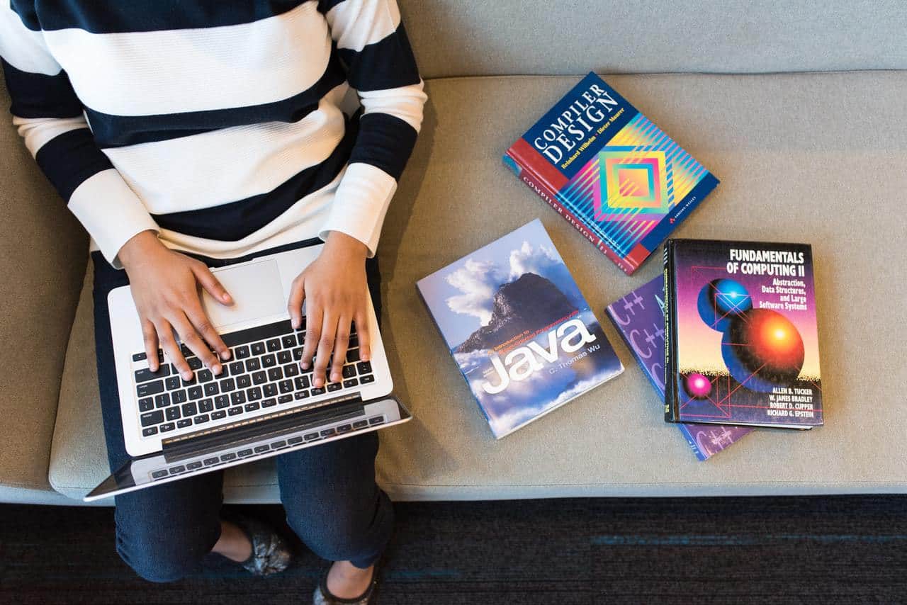 Woman with laptop and web development books