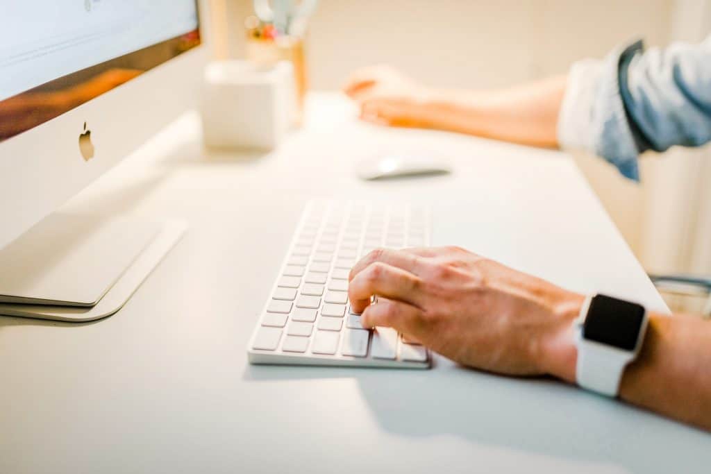 person with white apple watch working on pc