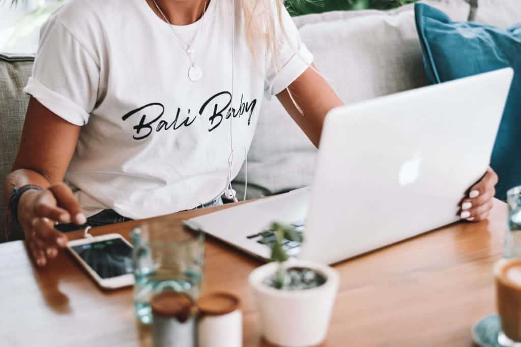 woman in white shirt using silver macbook