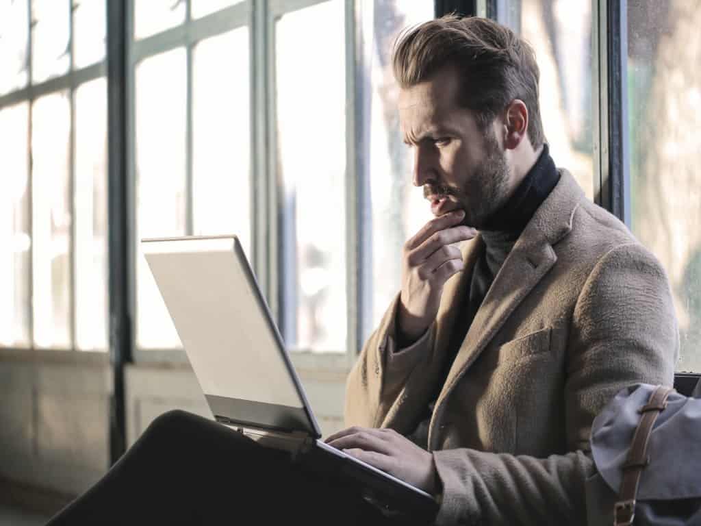 Man in the thinking pose with the laptop