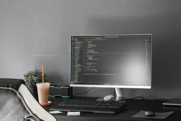 black flat screen computer monitor on black wooden desk AI coding assistant, code generation, developer with laptop