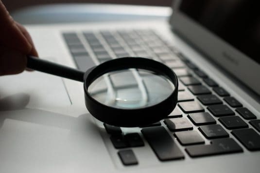 magnifying glass near gray laptop computer keyword research, walmart seller tools, data analysis