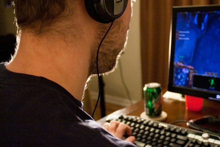 a man sitting in front of a computer with headphones on vr headset, gaming laptop, player immersed