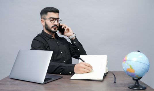 a man holding a pen and a book and a laptop user chatting with support, customer service representative, online help