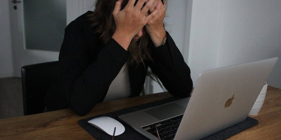 a woman covering her face while looking at a laptop frustrated customer, chatbot failure, unhappy client