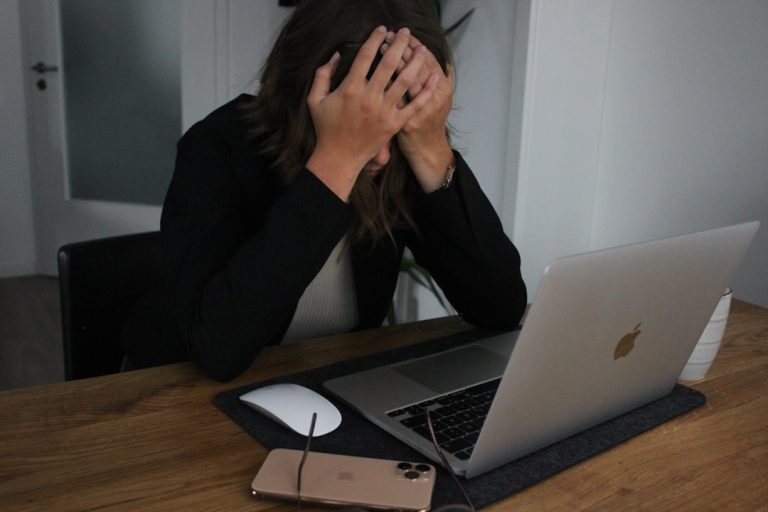 a woman covering her face while looking at a laptop frustrated customer, chatbot failure, unhappy client