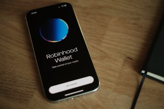 A cell phone sitting on top of a wooden table robinhood app, mobile wallet, crypto transfer