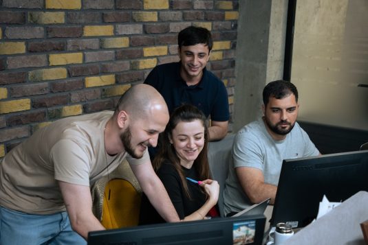 A group of people sitting around a laptop computer collaboration, coding community, team programming