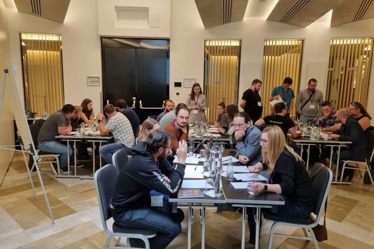 a group of people sitting around a table laptop camera usb team meeting