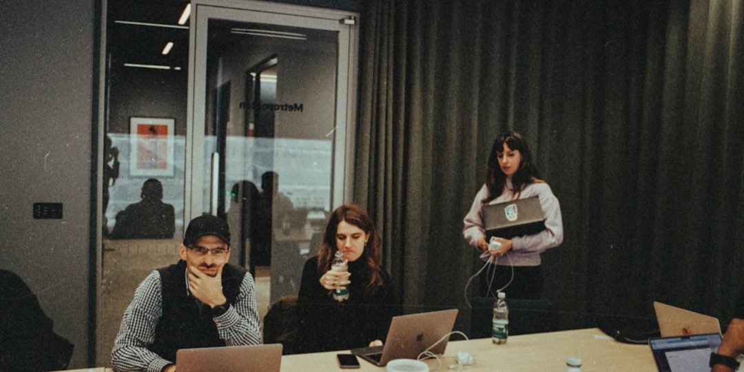 a group of people sitting around a table with laptops laptop camera usb team meeting