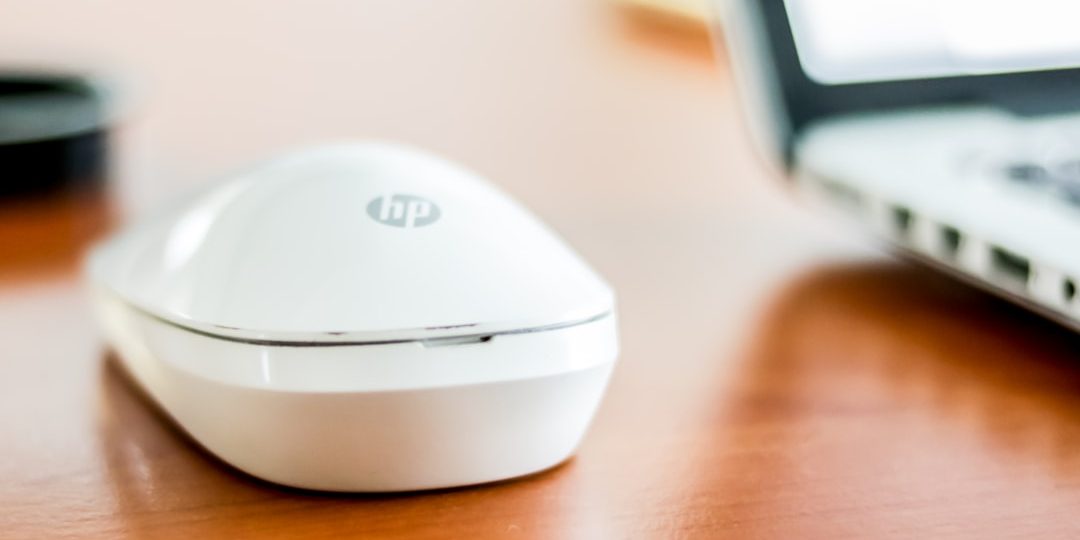 white HP cordless mouse on top of table beside laptop wifi 7, multi link, wireless technology