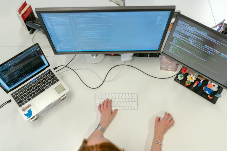 person using macbook pro on white table coding ipad terminal dev tools