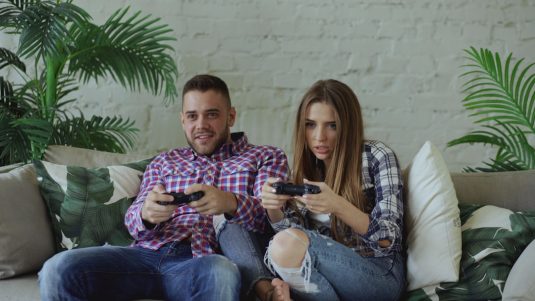 Couple playing video games on sofa gamers chatting, steampunk style, digital messaging