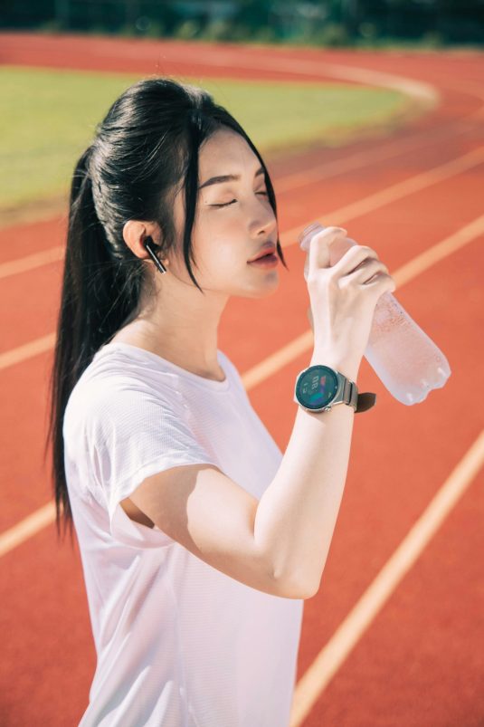 a woman drinking water while standing on a track fitness woman gym energy drink celsius