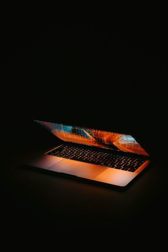 macbook pro on black table business technology digital transformation laptops collaboration