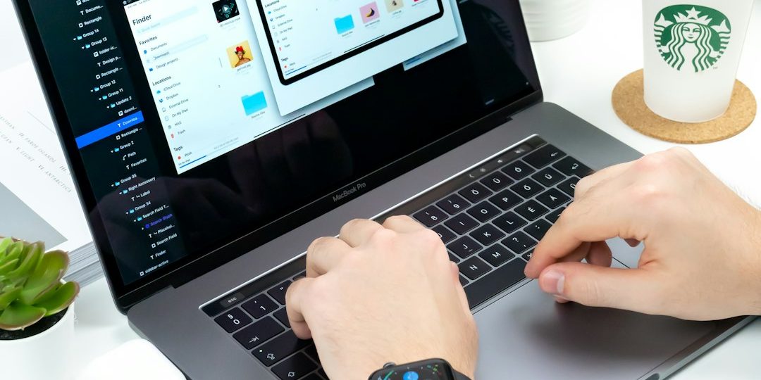 person using laptop between Starbucks cup and iPhone mac activity monitor, app processes, system overview